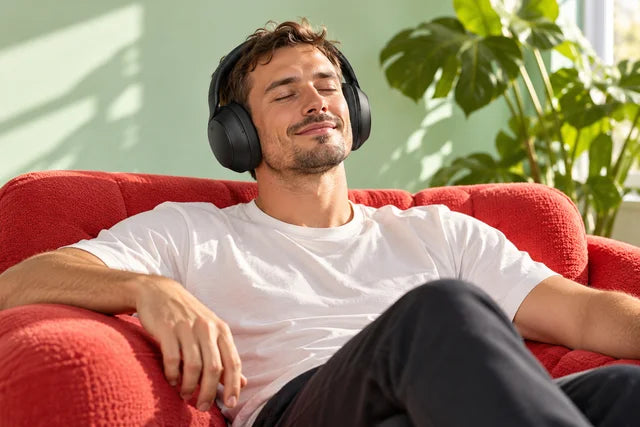 Listener relaxing in a red armchair wearing QuietMix II headphones